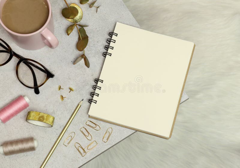 Het notitieboekje, gouden bureautoebehoren, kop van koffie, draden, glazen op het graniet dient en witte vloer in stock afbeelding Het notitieboekje, gouden bureautoebehoren, kop van koffie, draden, glazen op het graniet dient en witte vloer in stock afbeelding