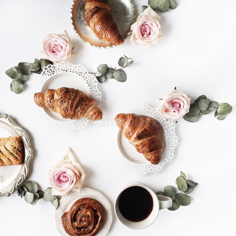 Het ontbijt met roze croissants, nam bloem, bloemblaadjes, uitstekende platen en zwarte koffiesamenstelling toe royalty-vrije stock afbeeldingen Het ontbijt met roze croissants, nam bloem, bloemblaadjes, uitstekende platen en zwarte koffiesamenstelling toe royalty-vrije stock afbeeldingen