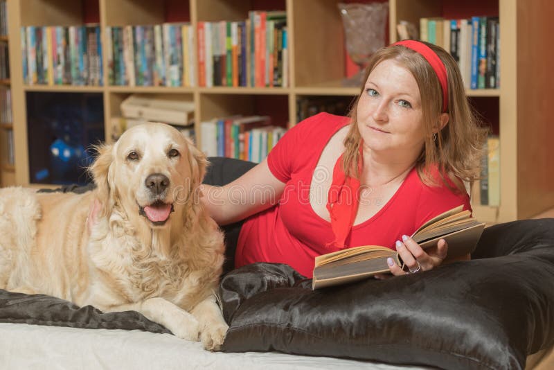 Het ontspannen met een hond en een boek die de camera bekijken royalty-vrije stock afbeelding Het ontspannen met een hond en een boek die de camera bekijken royalty-vrije stock afbeelding