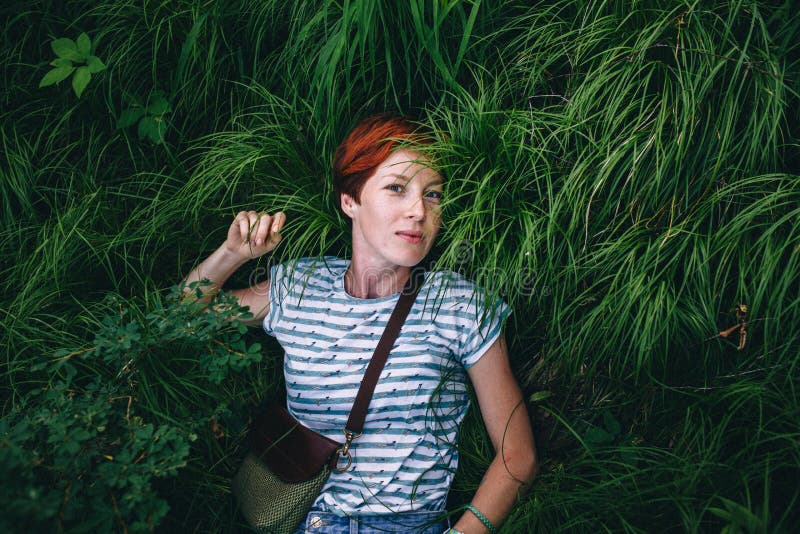 Het ontspannende roodharige hipster meisje ligt in het groene gras royalty-vrije stock fotografie Het ontspannende roodharige hipster meisje ligt in het groene gras royalty-vrije stock fotografie