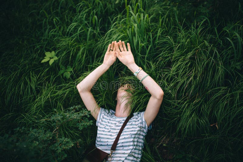 Het ontspannende roodharige hipster meisje ligt in het groene gras stock foto Het ontspannende roodharige hipster meisje ligt in het groene gras stock foto