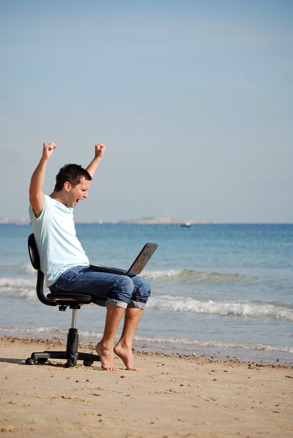 Young man cheering at laptop on the beach after winning on the internet. Young man cheering at laptop on the beach after winning on the internet
