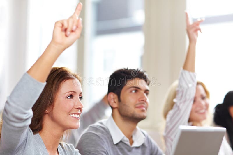 Two women raising hands in university class. Two women raising hands in university class