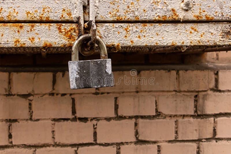 Het oude grijze slot van de hangslotveiligheid op een achtergrond van de metaal roestige doos en een bakstenen muur grunge achter royalty-vrije stock afbeelding Het oude grijze slot van de hangslotveiligheid op een achtergrond van de metaal roestige doos en een bakstenen muur grunge achter royalty-vrije stock afbeelding