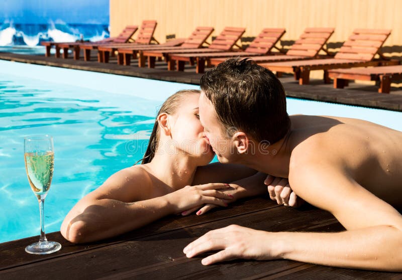 Het paar heeft een rust in de pool met champagne zij glimlachen, koesteren en kussen royalty-vrije stock afbeelding Het paar heeft een rust in de pool met champagne zij glimlachen, koesteren en kussen royalty-vrije stock afbeelding