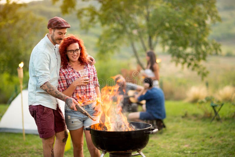Het paar in liefde het drinken bier en bereidt grillbrand voor stock foto's Het paar in liefde het drinken bier en bereidt grillbrand voor stock foto's