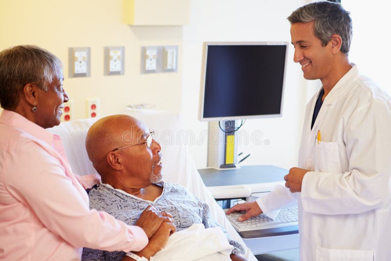 Doctor Talking To Senior Couple On Ward In Hospital Room Smiling At Each Other. Doctor Talking To Senior Couple On Ward In Hospital Room Smiling At Each Other