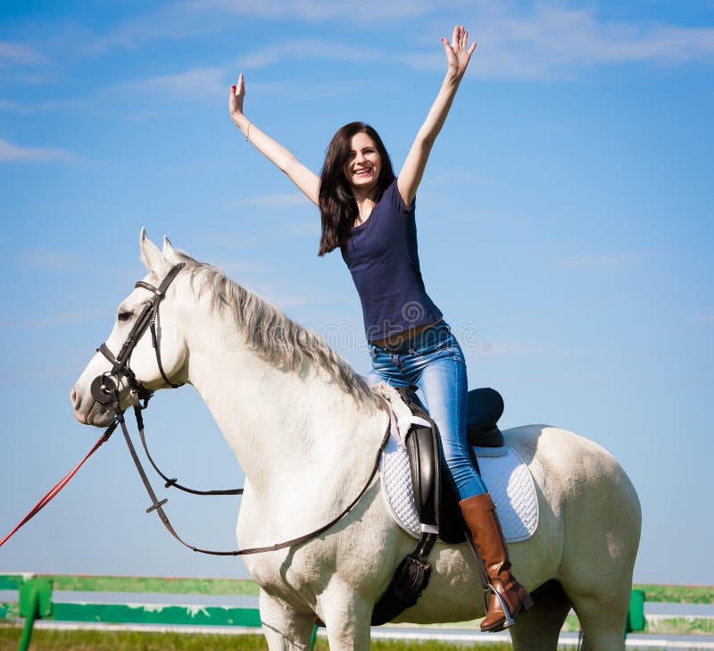 Het paard van de vrouwenzitting dag volledige hoogte Blauwe t-shirt en jeans stock afbeeldingen Het paard van de vrouwenzitting dag volledige hoogte Blauwe t-shirt en jeans stock afbeeldingen