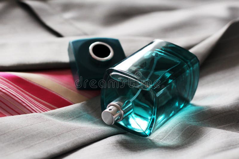 Het parfum van mensen in mooie fles op het grijze jasje stock foto Het parfum van mensen in mooie fles op het grijze jasje stock foto