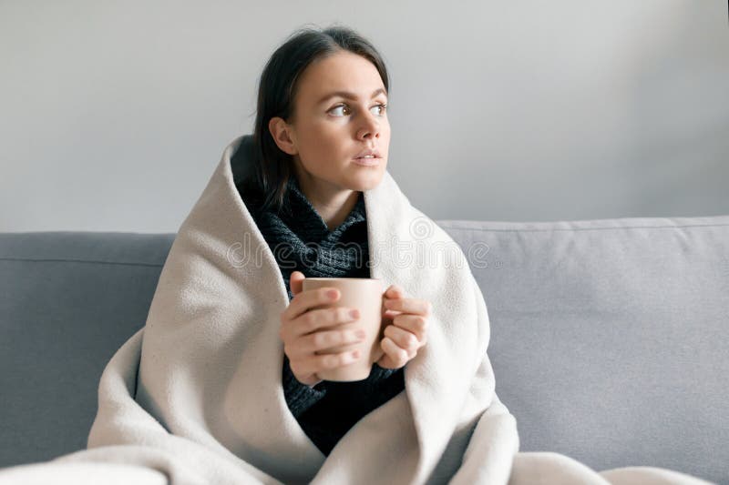 Het portret die van de de herfstwinter van jong meisje thuis op de bank met kop van hete drank, onder warme deken rusten royalty-vrije stock foto Het portret die van de de herfstwinter van jong meisje thuis op de bank met kop van hete drank, onder warme deken rusten royalty-vrije stock foto