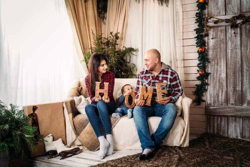 Het portret van de Kerstmisfamilie van jonge gelukkige glimlachende ouders en de kleine woonkamer van de zoons thuis vakantie stock foto's Het portret van de Kerstmisfamilie van jonge gelukkige glimlachende ouders en de kleine woonkamer van de zoons thuis vakantie stock foto's