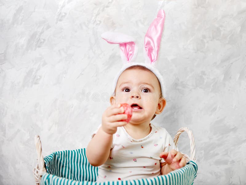 Het portret van een leuke baby gekleed in Paashaasoren in een mand houdt concept van ei het gelukkige Pasen royalty-vrije stock foto Het portret van een leuke baby gekleed in Paashaasoren in een mand houdt concept van ei het gelukkige Pasen royalty-vrije stock foto