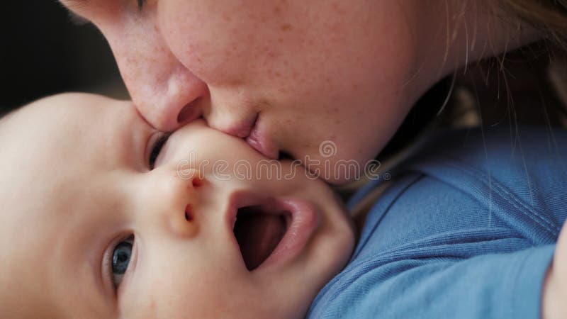 Het portret van een mooie vrouwen kussende baby, moeder kust dicht omhoog haar pasgeboren baby