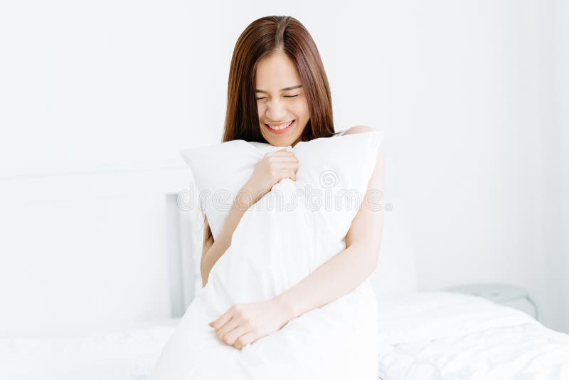 Het portret van glimlachende mooie jonge Aziatische vrouw die een hoofdkussen houden en sluit uw oog op bed Goedemorgen, nieuwe d stock foto Het portret van glimlachende mooie jonge Aziatische vrouw die een hoofdkussen houden en sluit uw oog op bed Goedemorgen, nieuwe d stock foto