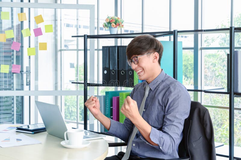 Het portret van jonge Aziatische zegevierend zakenman en viert met wapens omhoog voor baansucces in bureau royalty-vrije stock foto Het portret van jonge Aziatische zegevierend zakenman en viert met wapens omhoog voor baansucces in bureau royalty-vrije stock foto