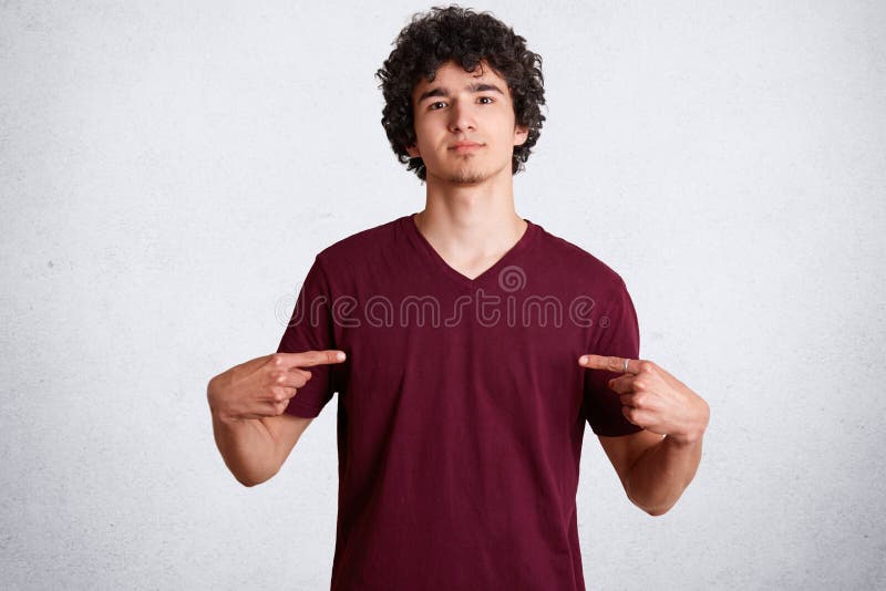 Het portret van knap jong mannetje wijst op bij lege ruimte van toevallige t-shirt voor uw reclame of ontwerpend inhoud, heeft ch royalty-vrije stock fotografie Het portret van knap jong mannetje wijst op bij lege ruimte van toevallige t-shirt voor uw reclame of ontwerpend inhoud, heeft ch royalty-vrije stock fotografie