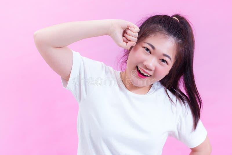 Het portret van mooi Jong Aziatisch vrouwen zwart haar draagt een witte die t-shirt op roze achtergrond wordt geïsoleerd royalty-vrije stock foto's Het portret van mooi Jong Aziatisch vrouwen zwart haar draagt een witte die t-shirt op roze achtergrond wordt geïsoleerd royalty-vrije stock foto's