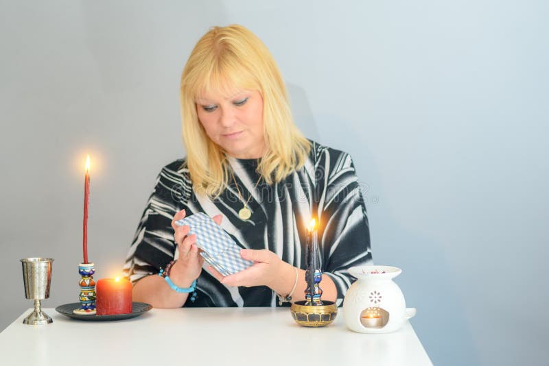 Het portret van mooie middenleeftijdsvrouw zit dichtbij een bureau van de fortuinteller met een tarotkaarten en kaarsen royalty-vrije stock afbeelding Het portret van mooie middenleeftijdsvrouw zit dichtbij een bureau van de fortuinteller met een tarotkaarten en kaarsen royalty-vrije stock afbeelding