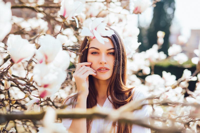 Het portret van mooie vrouw ontspant in mooie tuin van roze magnolia's die bij de lentetijd tot bloei komen stock foto Het portret van mooie vrouw ontspant in mooie tuin van roze magnolia's die bij de lentetijd tot bloei komen stock foto