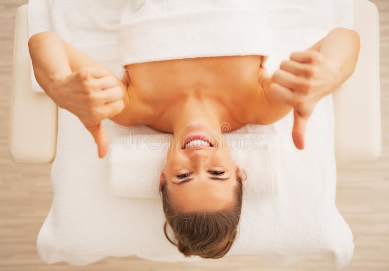 Het portret van vrouw het leggen op massagelijst en het tonen beduimelt omhoog stock foto's Het portret van vrouw het leggen op massagelijst en het tonen beduimelt omhoog stock foto's