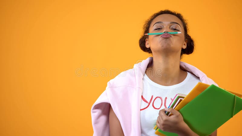 Het positieve Afrikaanse potlood van de tienerholding tussen neus en lippen, snorgrap royalty-vrije stock afbeeldingen Het positieve Afrikaanse potlood van de tienerholding tussen neus en lippen, snorgrap royalty-vrije stock afbeeldingen
