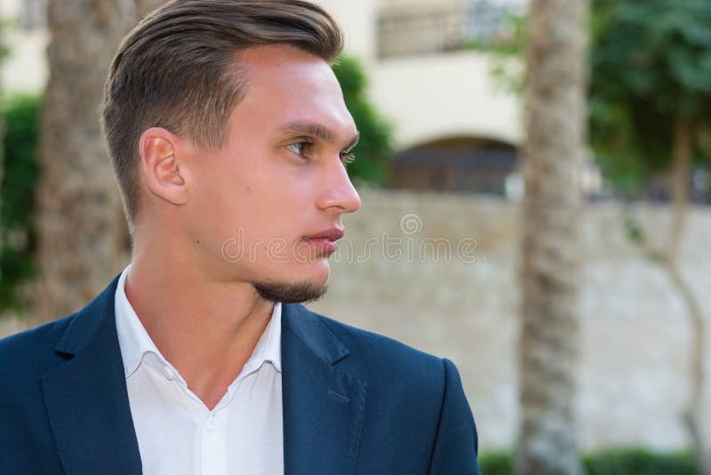 Het profielportret van een jonge knappe mens in een wit overhemd, wit broeken en een kostuum bevindt zich dichtbij de palm Manneq stock afbeeldingen Het profielportret van een jonge knappe mens in een wit overhemd, wit broeken en een kostuum bevindt zich dichtbij de palm Manneq stock afbeeldingen