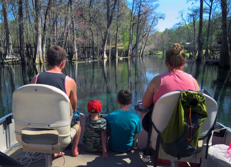 A mother and her three sons 16, 14 and 6 sit on the bow of the pontoon boat looking at the fish and turtles below in the crystal clear waters of Ichetucknee River near Fort White, Florida. A mother and her three sons 16, 14 and 6 sit on the bow of the pontoon boat looking at the fish and turtles below in the crystal clear waters of Ichetucknee River near Fort White, Florida.