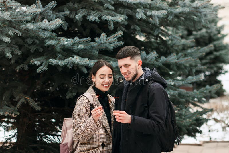 Het romantische jonge paar heeft in openlucht pret in de winter vóór Kerstmis met de lichten van Bengalen royalty-vrije stock foto Het romantische jonge paar heeft in openlucht pret in de winter vóór Kerstmis met de lichten van Bengalen royalty-vrije stock foto