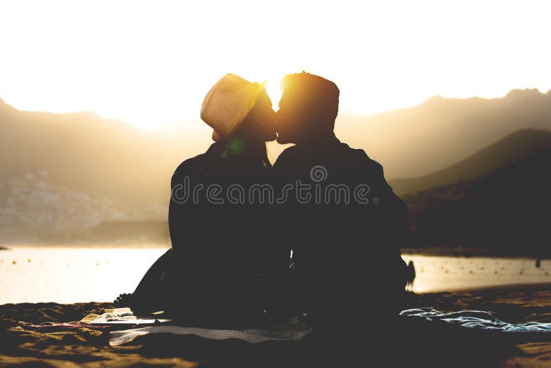 Het romantische jonge paar kussen op het strand op zonsondergang - Silhouet van tienerjarenminnaars aan het begin van hun verhaal royalty-vrije stock afbeeldingen Het romantische jonge paar kussen op het strand op zonsondergang - Silhouet van tienerjarenminnaars aan het begin van hun verhaal royalty-vrije stock afbeeldingen