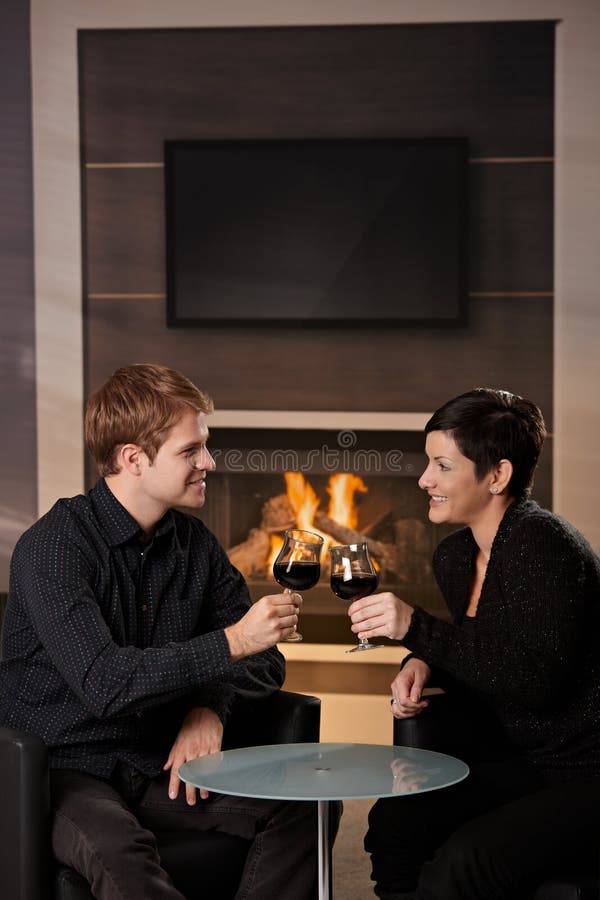 Young romentic couple dating, sitting in front of fireplace at home, drinking red wine. Young romentic couple dating, sitting in front of fireplace at home, drinking red wine.