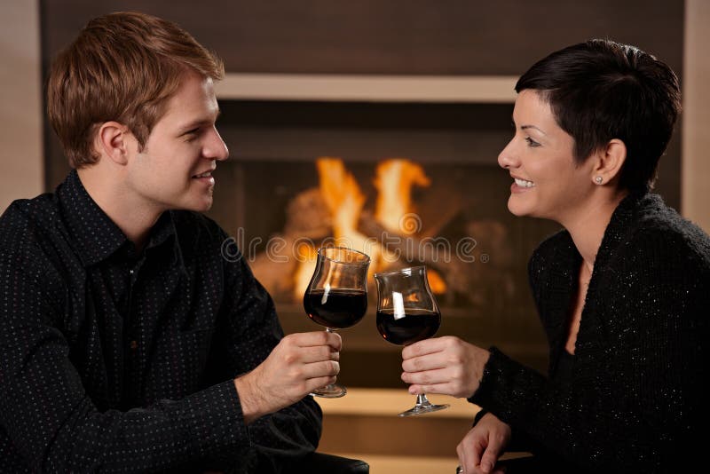 Young romantic couple dating, sitting in front of fireplace at home, drinking red wine. Young romantic couple dating, sitting in front of fireplace at home, drinking red wine.
