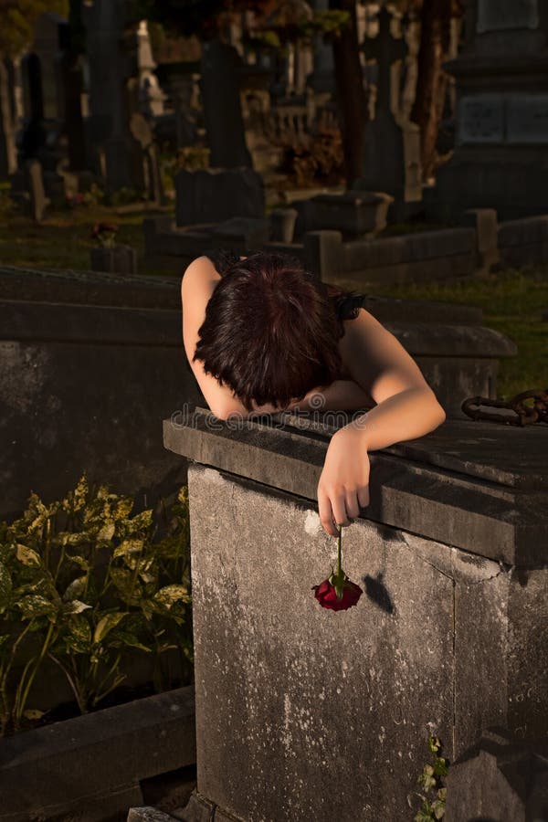 Night shot of a gothic young woman crying on a grave. Night shot of a gothic young woman crying on a grave