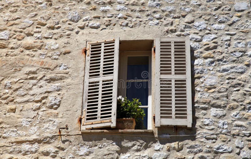 French rustic window with old wood shutters in stone rural house, Provence, France. French rustic window with old wood shutters in stone rural house, Provence, France.