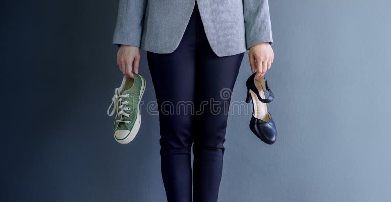 Work Life Balance Concept, present by Business Working Woman holding a High Heal and Sneaker Shoes, Croped image with Copy Space. Work Life Balance Concept, present by Business Working Woman holding a High Heal and Sneaker Shoes, Croped image with Copy Space