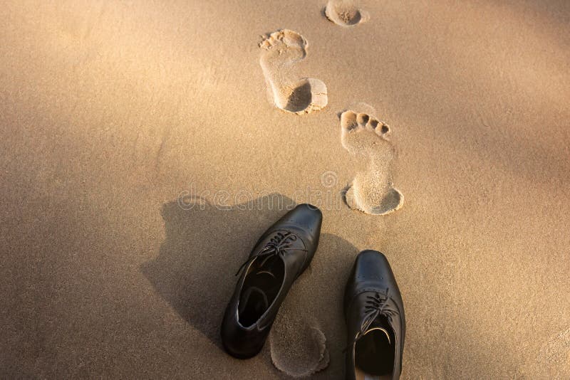 Work Life Balance Concept, Businessman take off his Working Oxford Shoes and leave it on the Sand Beach near the Rock for Walk into the Sea on Sunny Day. Top View. Work Life Balance Concept, Businessman take off his Working Oxford Shoes and leave it on the Sand Beach near the Rock for Walk into the Sea on Sunny Day. Top View