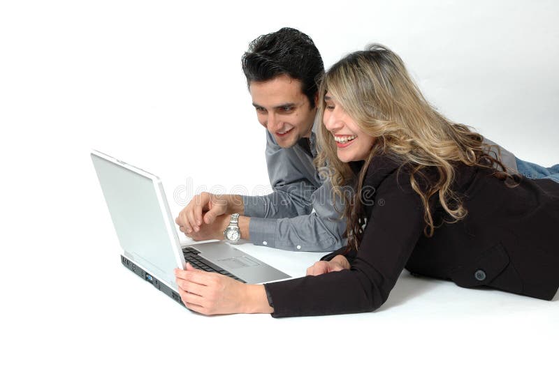 A Happy Diverse couple on white background laying on the floor and doing internet shopping. Facial expressions of shopping consumers. Couple playfully fighting over the computer. A Happy Diverse couple on white background laying on the floor and doing internet shopping. Facial expressions of shopping consumers. Couple playfully fighting over the computer.