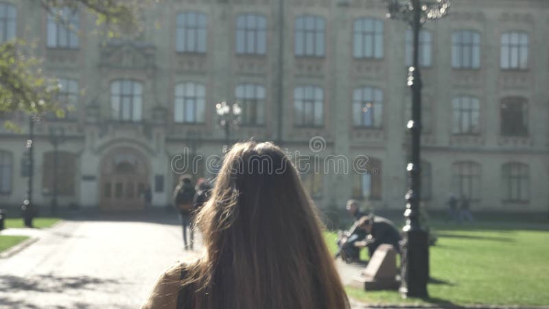 Het schieten van achter, mooie Kaukasische vrouw loopt vooruit in zich stedelijk stadsgebied, het zonnige aardige weer en bewegen