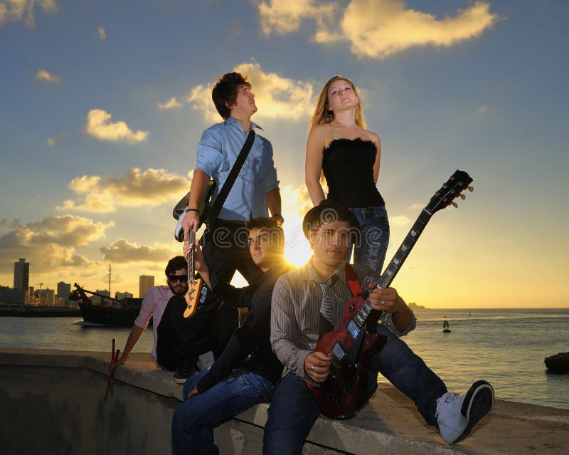 Het schitterende tiener muzikale band stellen bij zonsondergang royalty-vrije stock foto Het schitterende tiener muzikale band stellen bij zonsondergang royalty-vrije stock foto