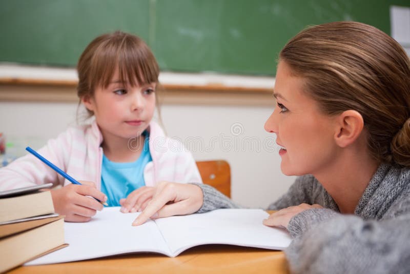 Het schoolmeisje dat een tijdje haar leraar schrijft spreekt stock foto's Het schoolmeisje dat een tijdje haar leraar schrijft spreekt stock foto's
