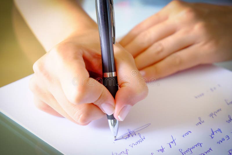 Girl Writing down a letter on a white sheet of paper with a black pen. Girl Writing down a letter on a white sheet of paper with a black pen.