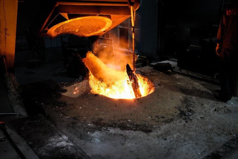 Het smeltende metaal van de gieterijarbeider voor het gieten van vervangstukken stock foto Het smeltende metaal van de gieterijarbeider voor het gieten van vervangstukken stock foto