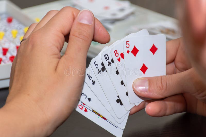Het spel die van de de kaartopeenvolging van de familiepret een hand of kaarten tonen die over schouder van een mamma kijken die royalty-vrije stock fotografie Het spel die van de de kaartopeenvolging van de familiepret een hand of kaarten tonen die over schouder van een mamma kijken die royalty-vrije stock fotografie
