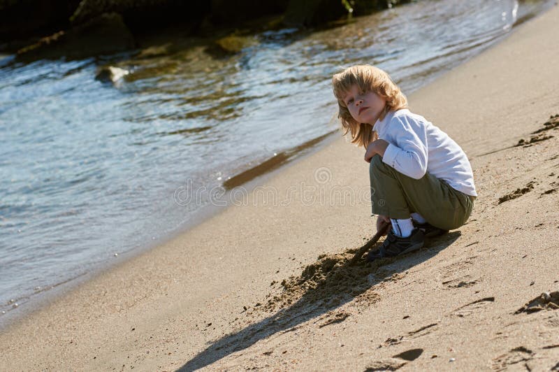 Het spelen van de jongen met het zand op het strand royalty-vrije stock afbeeldingen Het spelen van de jongen met het zand op het strand royalty-vrije stock afbeeldingen