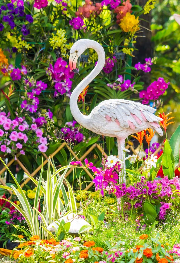 Flamingo standbeeld in een bloementuin stock afbeeldingen