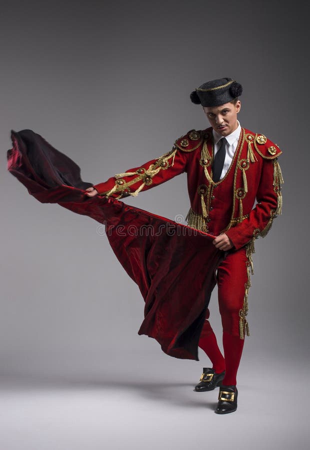 Studio shot of man dressed as Spanish torero, matador, bullfighter. Performing a traditional classic bullfight, standing and holding the capote. Studio shot of man dressed as Spanish torero, matador, bullfighter. Performing a traditional classic bullfight, standing and holding the capote.
