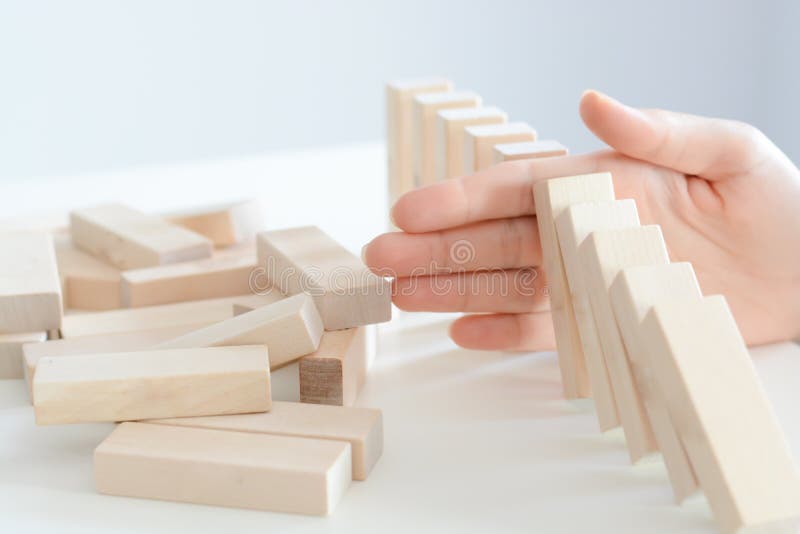 Stopping the domino effect of wooden blocks concept with a business solution and intervention. Stopping the domino effect of wooden blocks concept with a business solution and intervention
