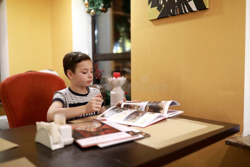 Jongen bekijkt een tijdschrift in een café royalty-vrije stock fotografie