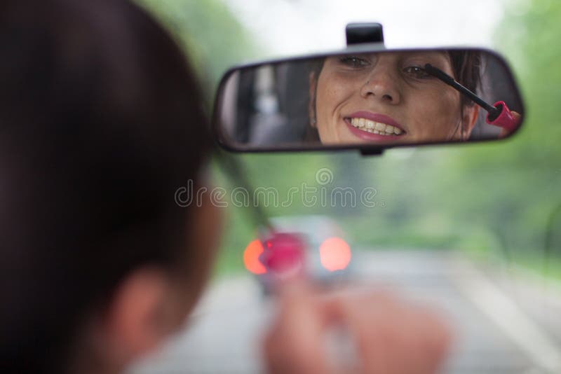 Het toepassen van mascara terwijl het drijven van een auto stock foto's Het toepassen van mascara terwijl het drijven van een auto stock foto's
