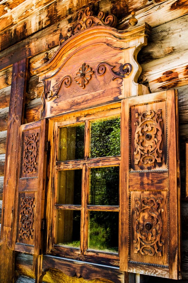 In het Venster van een blokhuis open blindenvenster in een blokhuis in het platteland Houten gesneden blinden op het venster stock foto In het Venster van een blokhuis open blindenvenster in een blokhuis in het platteland Houten gesneden blinden op het venster stock foto
