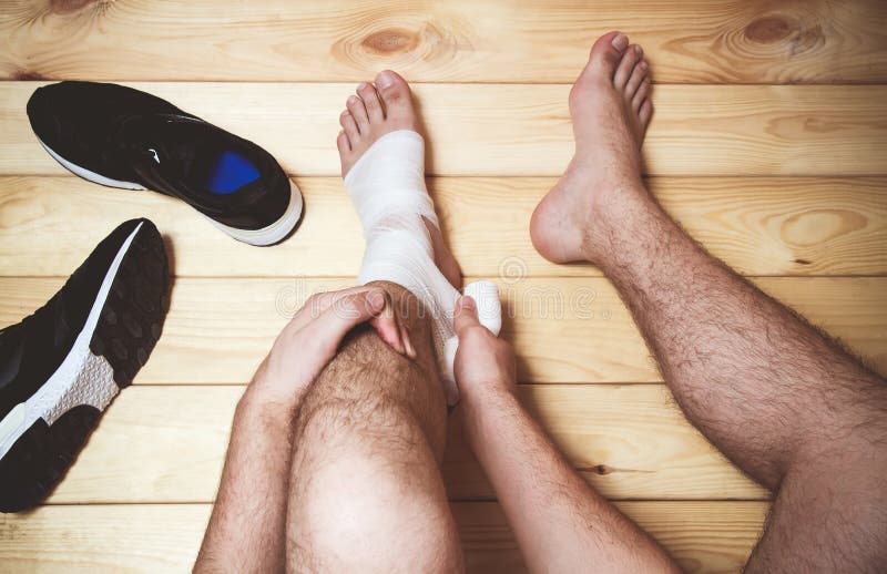 Man leg bandage sitting on the wooden floor. Sports injuries. top view. Man leg bandage sitting on the wooden floor. Sports injuries. top view